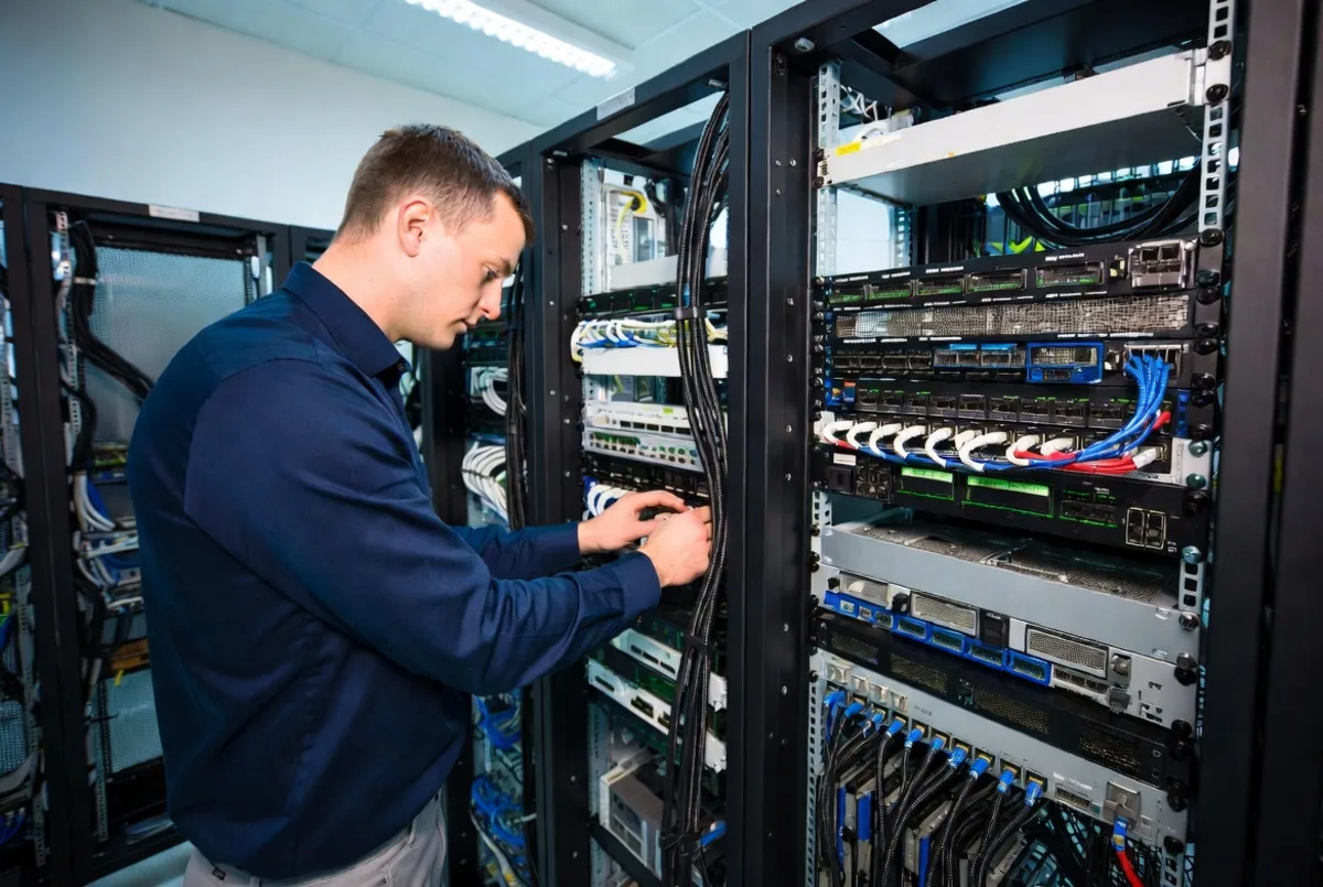 An engineer cabling a network rack
