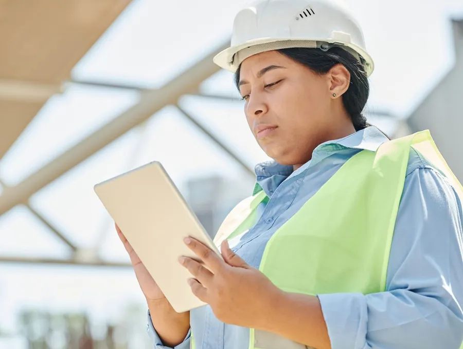 A construction worker reviewing plans on a tablet onsite — Braintek construction IT