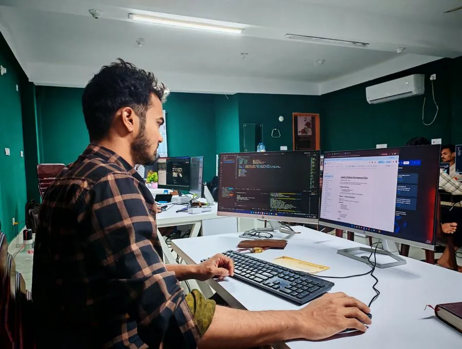 A Braintek developer building and reviewing custom software at dual code monitors